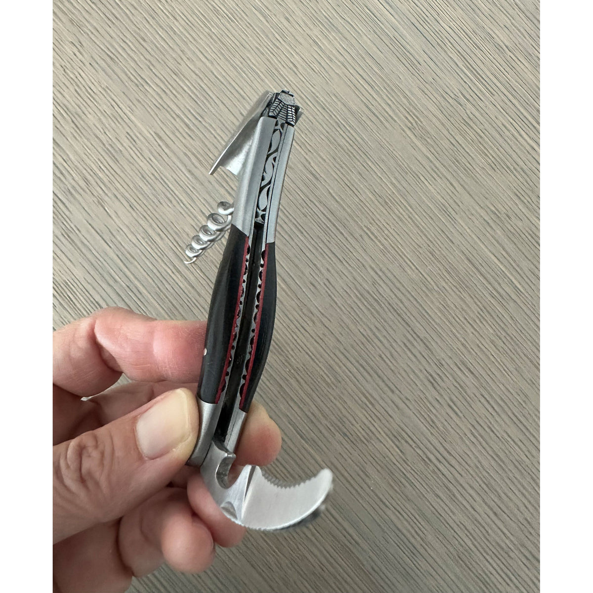 Hand holding the corkscrew with the foil cutter extended