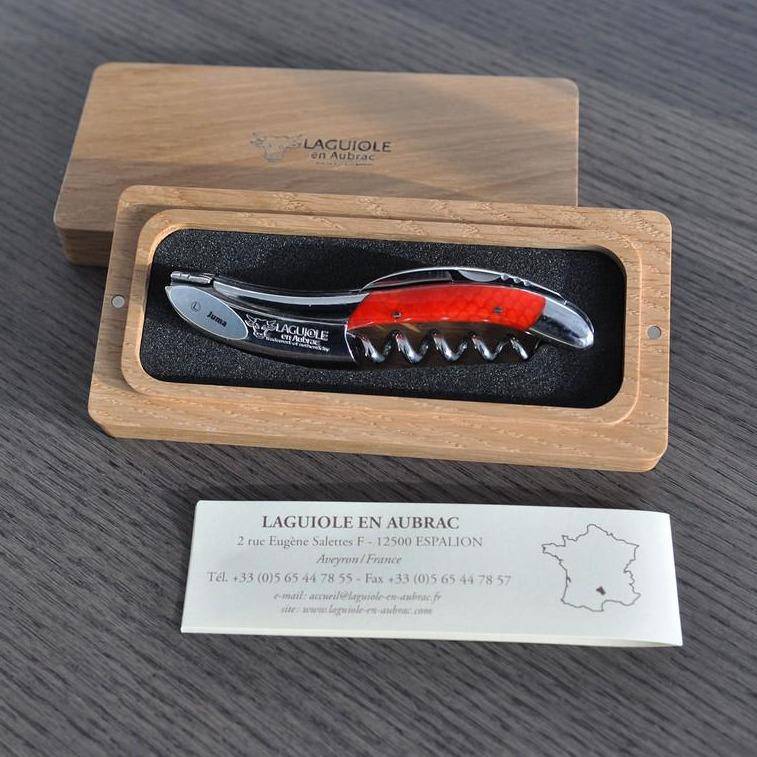 Orange handled corkscrew in an open oak box with the certificate card below