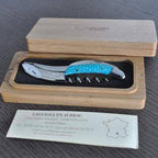 Turquoise handled corkscrew in an open oak box with the Laguiole en Aubrac certificate card