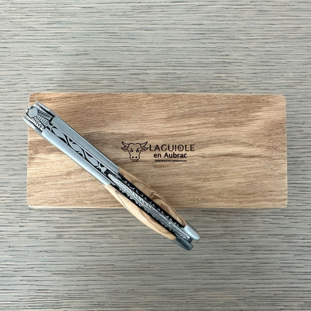 Folded corkscrew resting across the oak box lid