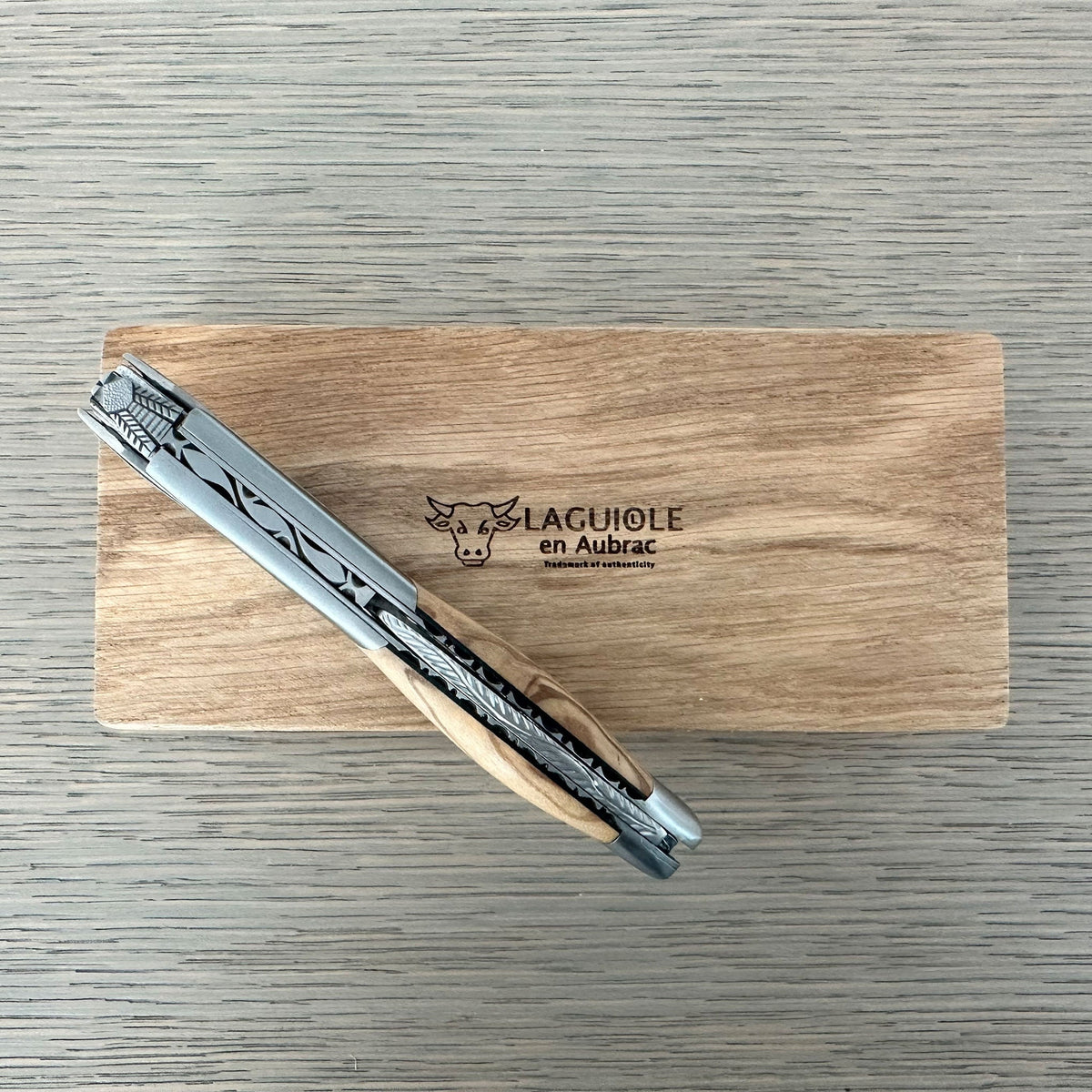 Folded corkscrew resting across the oak box lid