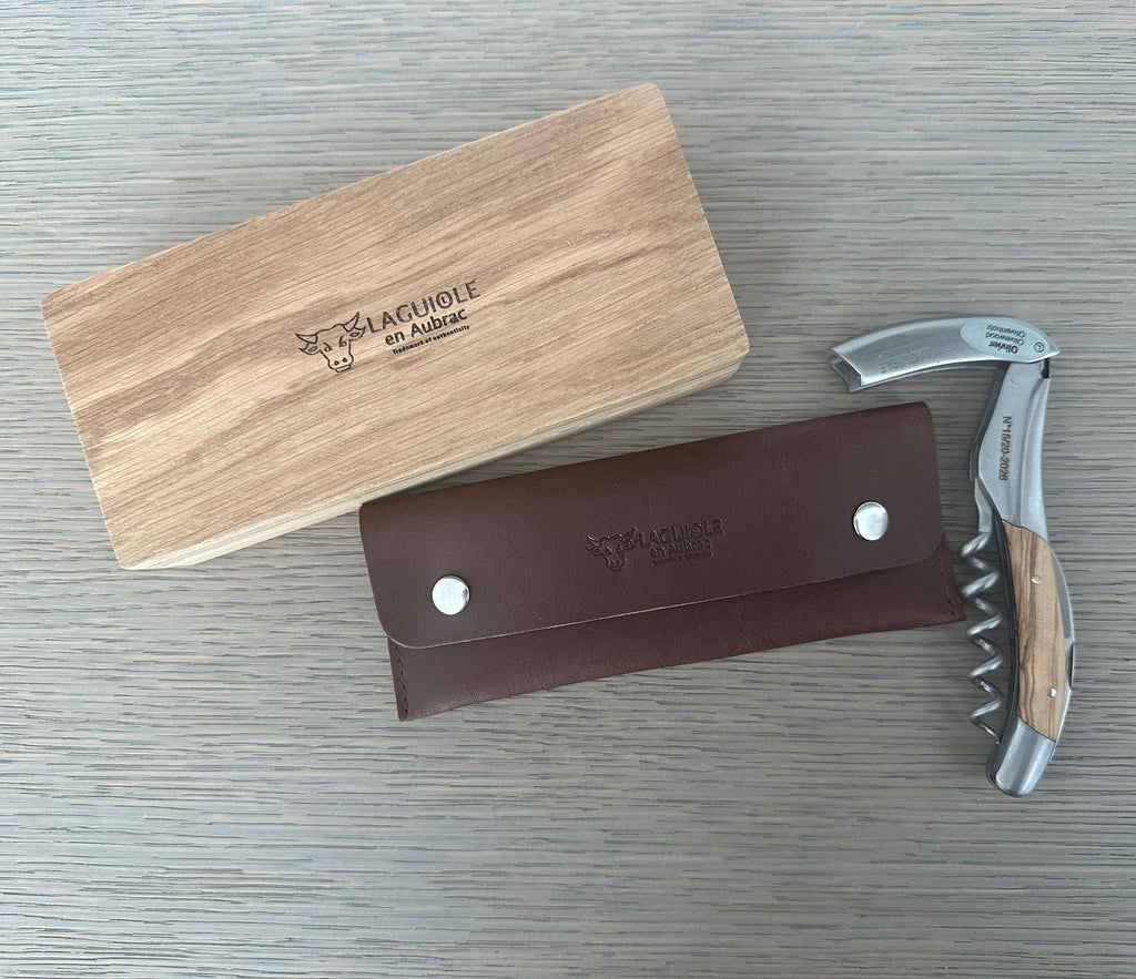 Oak box lid, brown leather pouch and corkscrew together on grey