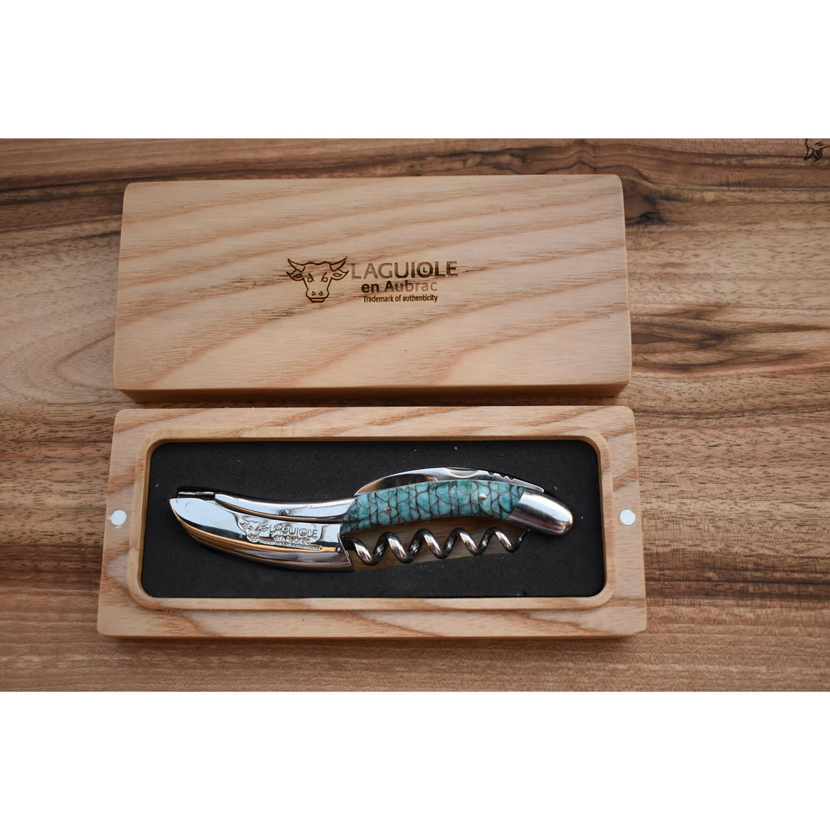 Turquoise handled corkscrew in an open oak gift box on a wood table