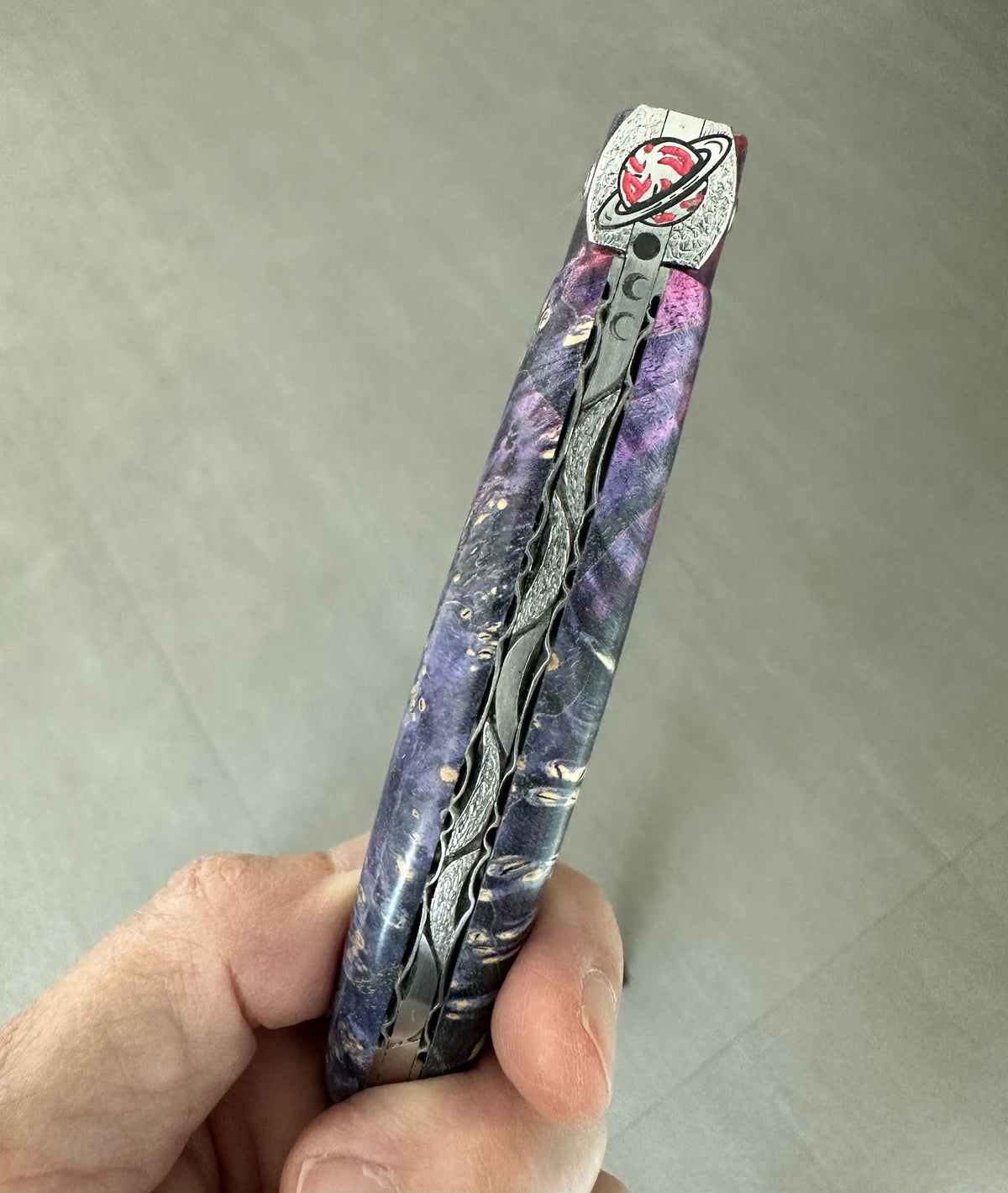 Hand holding the knife to show the engraved spring and bee
