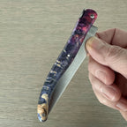 Hand folding the knife to show the purple burl handle