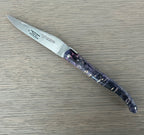 Open knife lying diagonally on a pale wood surface