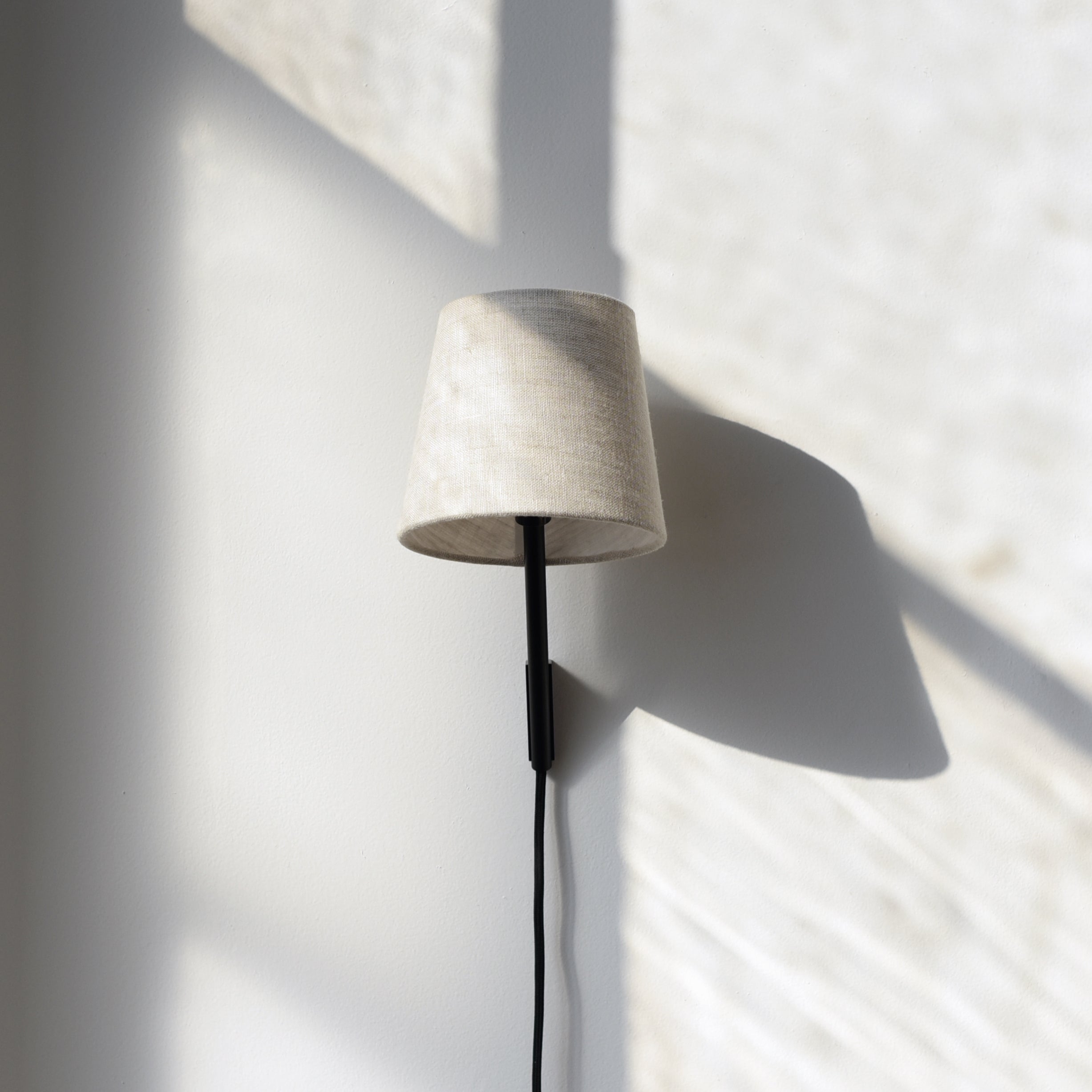 adjustable plug in wall sconce beside a bed