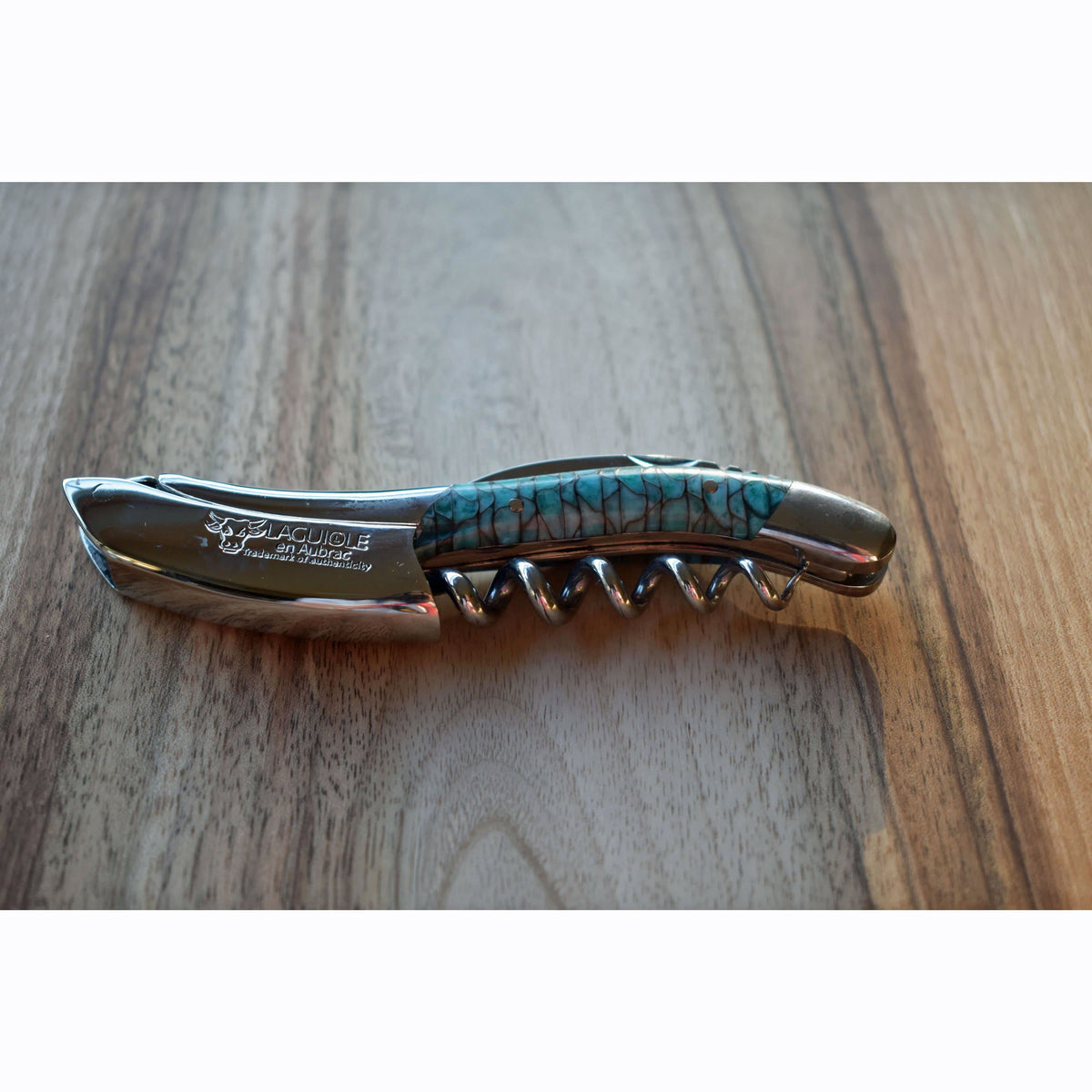Folded corkscrew lying on a warm wood surface