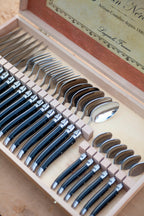 Close-up of Laguiole Jean Néron black-handled forks, knives, and spoons in open wooden box