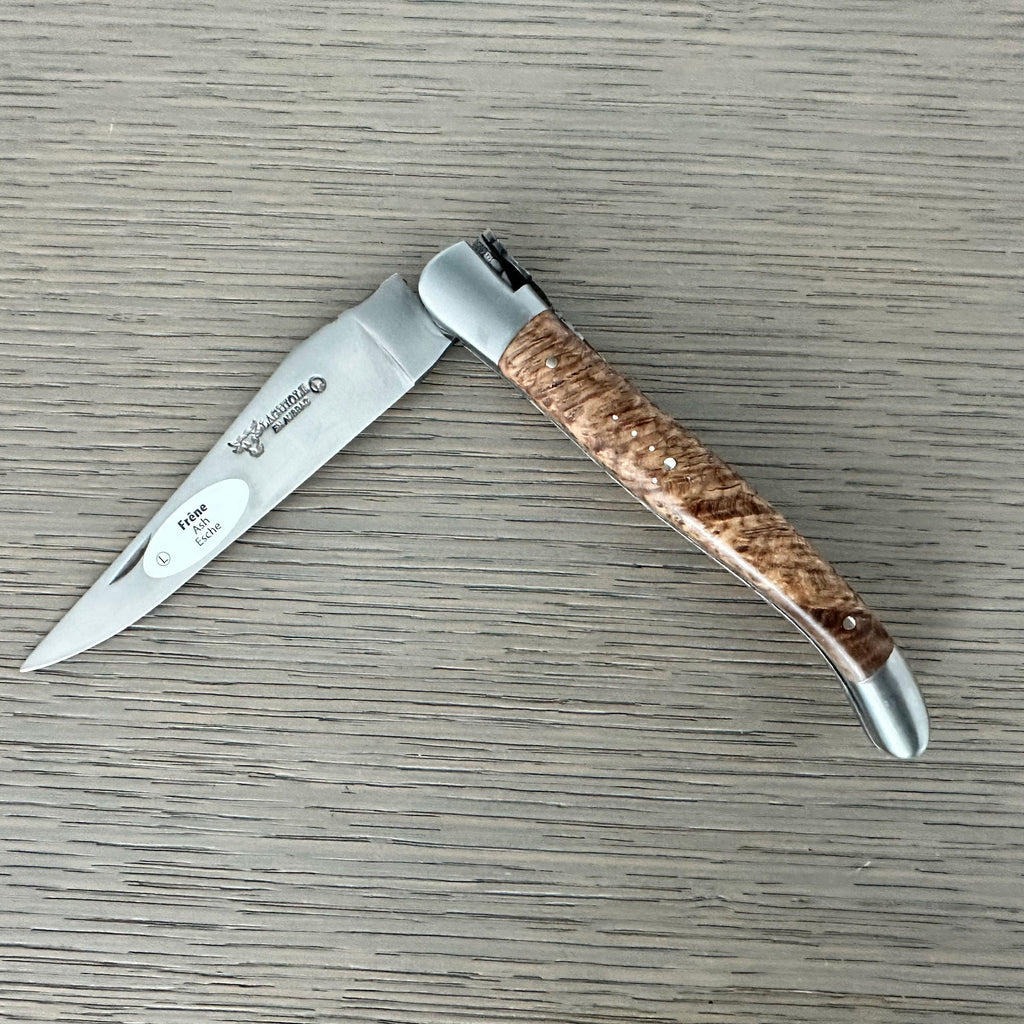 Laguiole ash burl folding knife half open on a grey wood surface