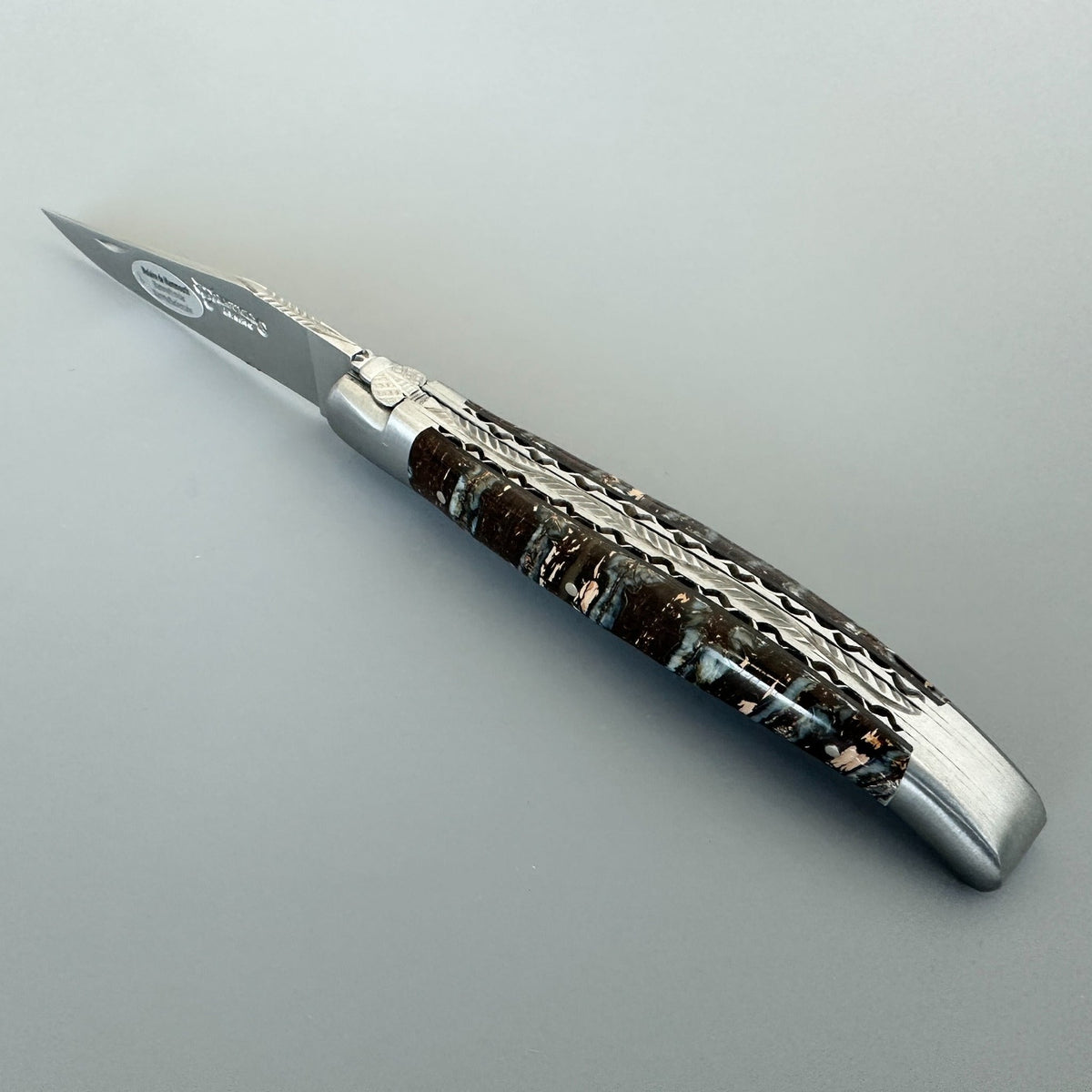Open knife against a grey background showing the filed plates