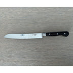 Laguiole forged bread knife with black ebony handle on a grey wood surface