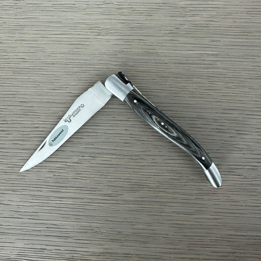Laguiole grey pakka folding knife half open on a pale wood surface