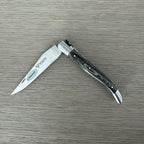 Laguiole grey pakka folding knife half open on a pale wood surface