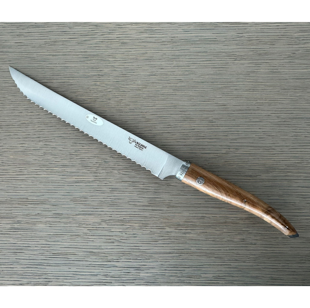 Laguiole serrated bread knife with teak handle on a grey wood surface