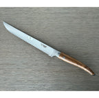 Laguiole serrated bread knife with teak handle on a grey wood surface