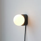 minimalist ceramic wall sconce mounted beside a mirror