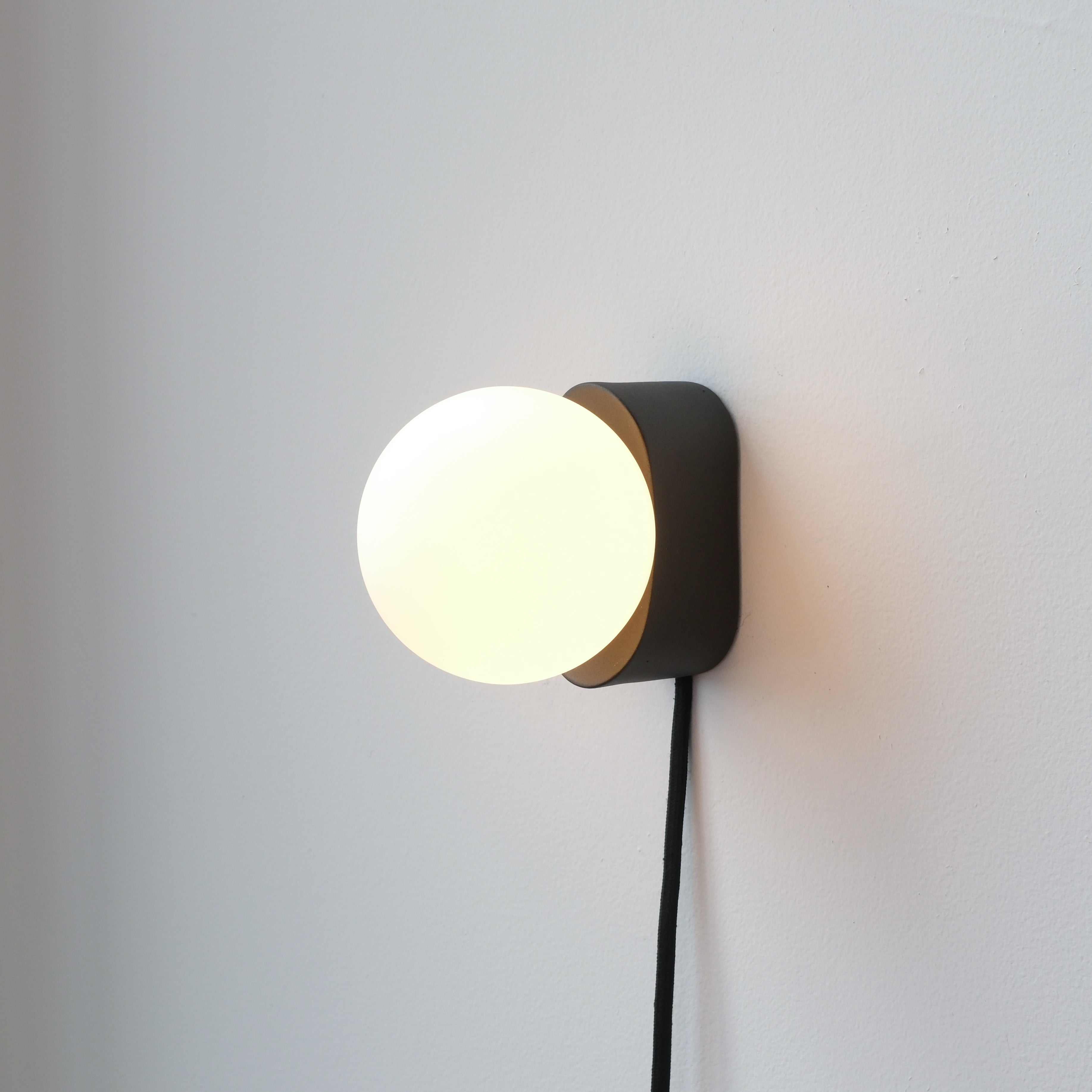 minimalist ceramic wall sconce mounted beside a mirror